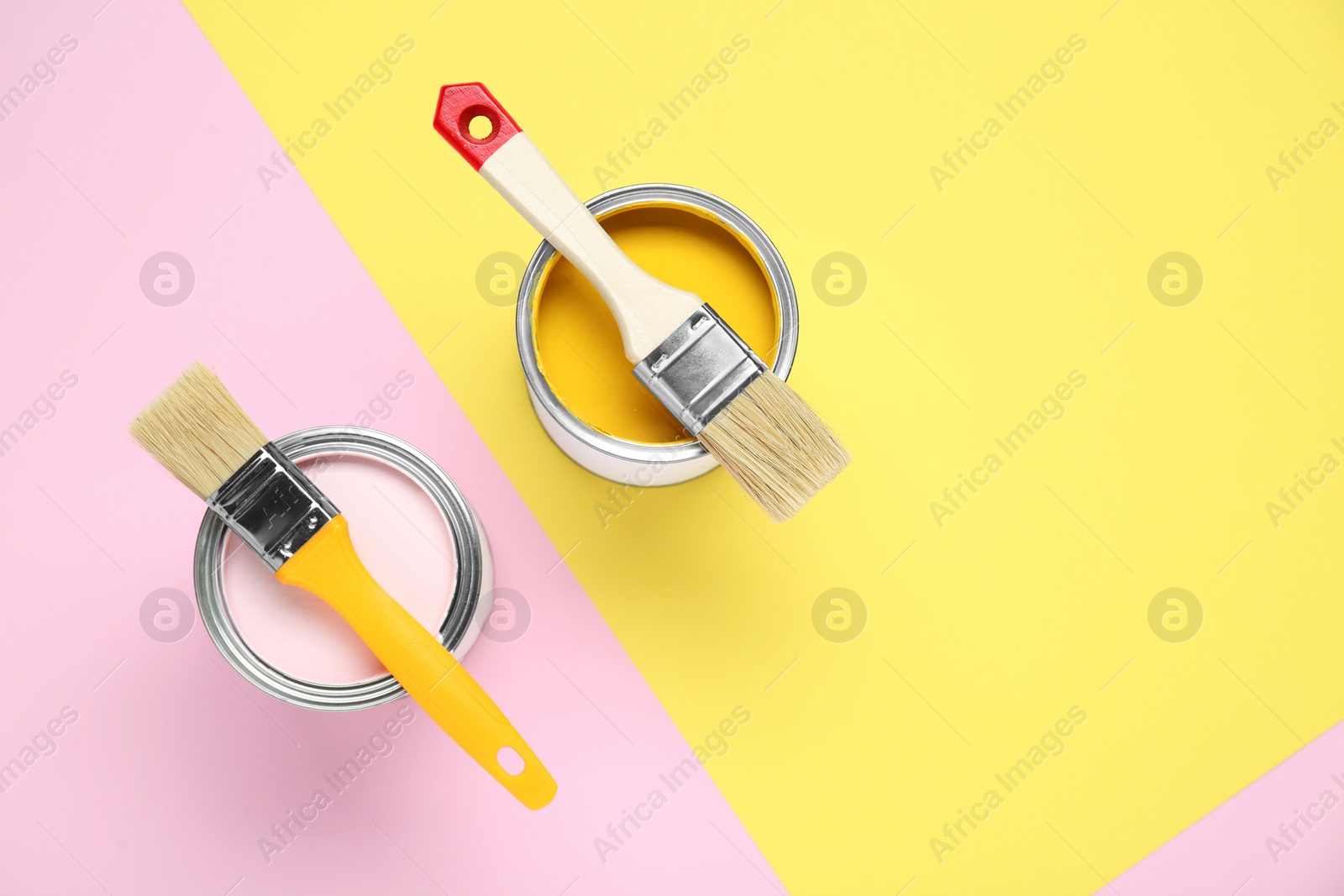 Photo of Cans of different paints with brushes on color background, flat lay. Space for text