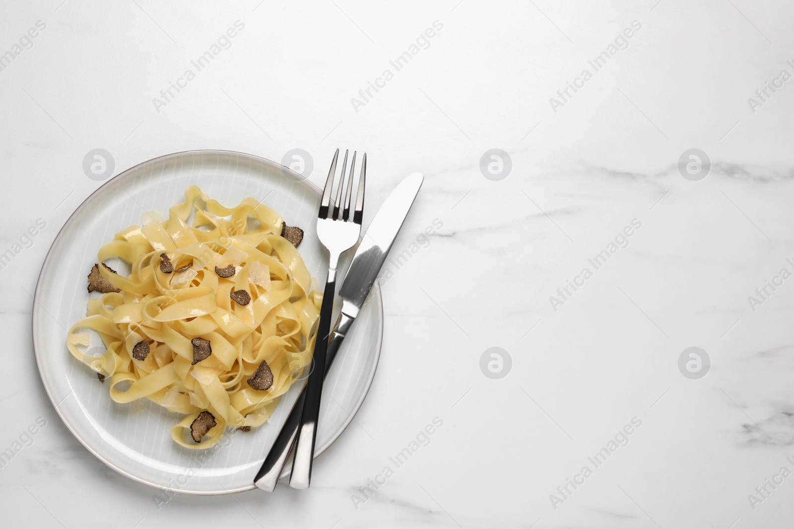 Photo of Delicious pasta with truffle slices on white table, top view. Space for text
