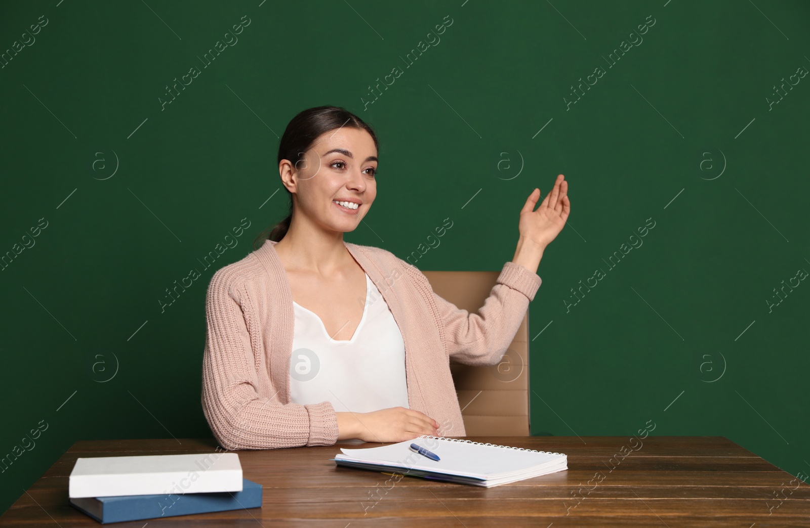 Photo of Portrait of young teacher at table against green background