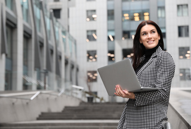 Photo of Beautiful woman in stylish suit with laptop outdoors. Space for text