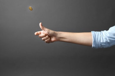 Young woman throwing coin on grey background, closeup