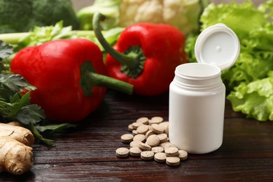 Photo of Dietary supplements. Plastic bottle, pills and food products on wooden table