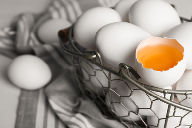 Photo of Chicken eggs in metal basket on table, closeup