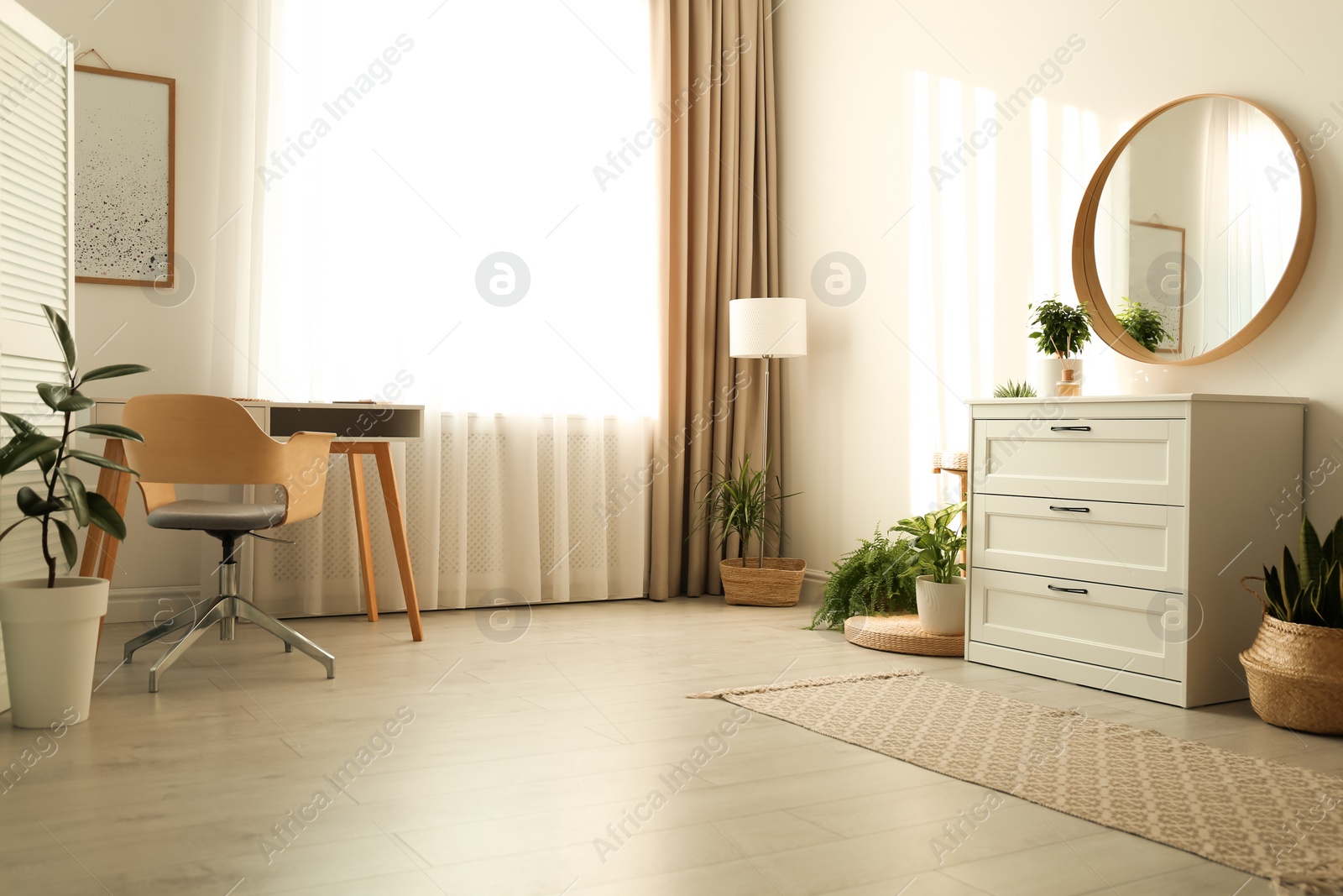 Photo of Stylish room interior with chest of drawers and round mirror