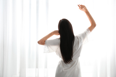 Photo of Young woman near window at home. Lazy morning