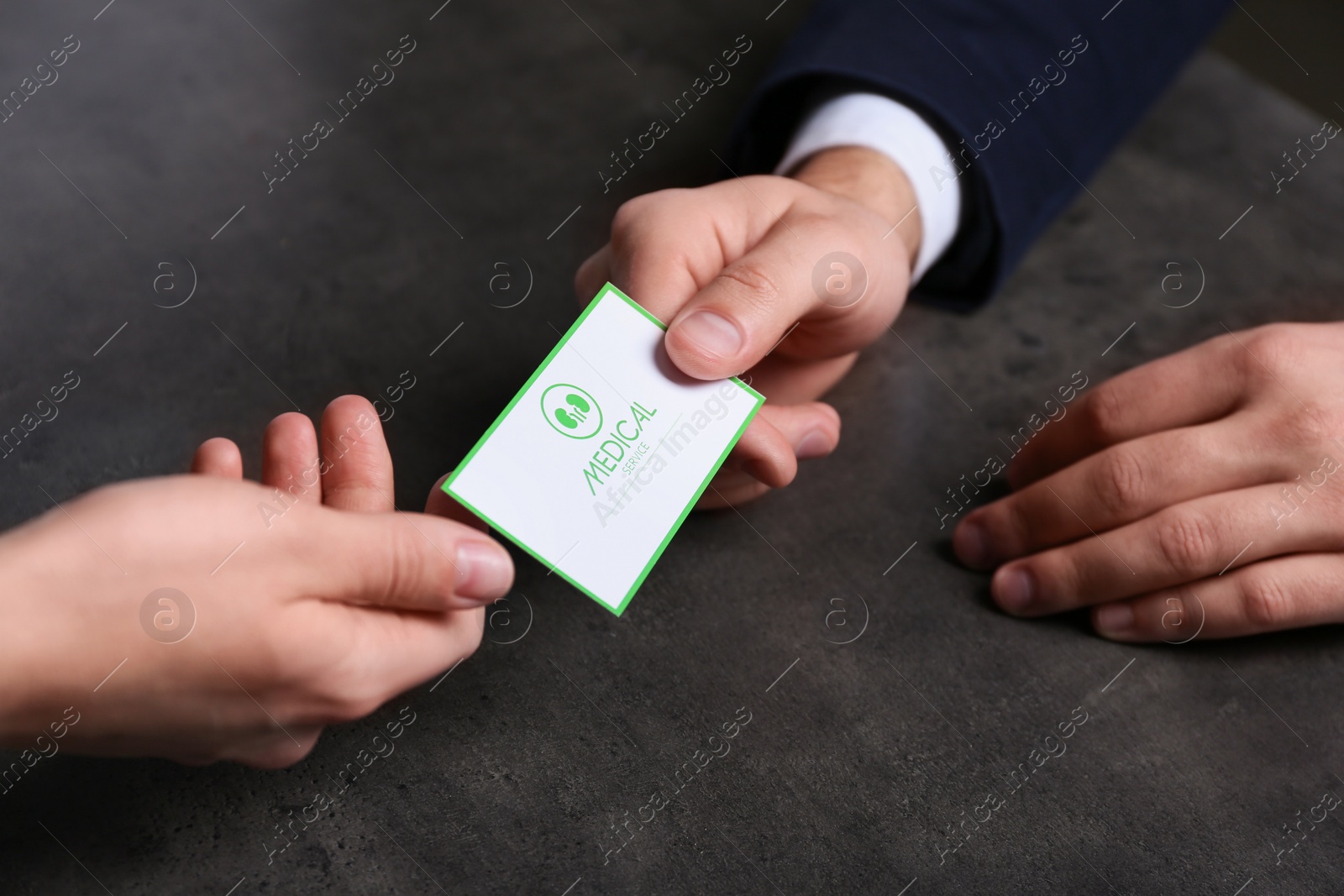 Photo of Man giving medical business card to woman on dark background, closeup. Nephrology service