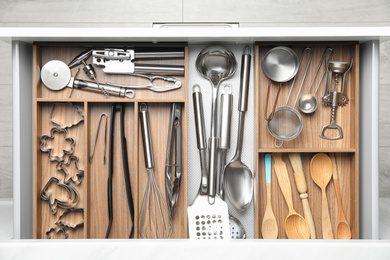 Photo of Different utensils in open desk drawer, top view