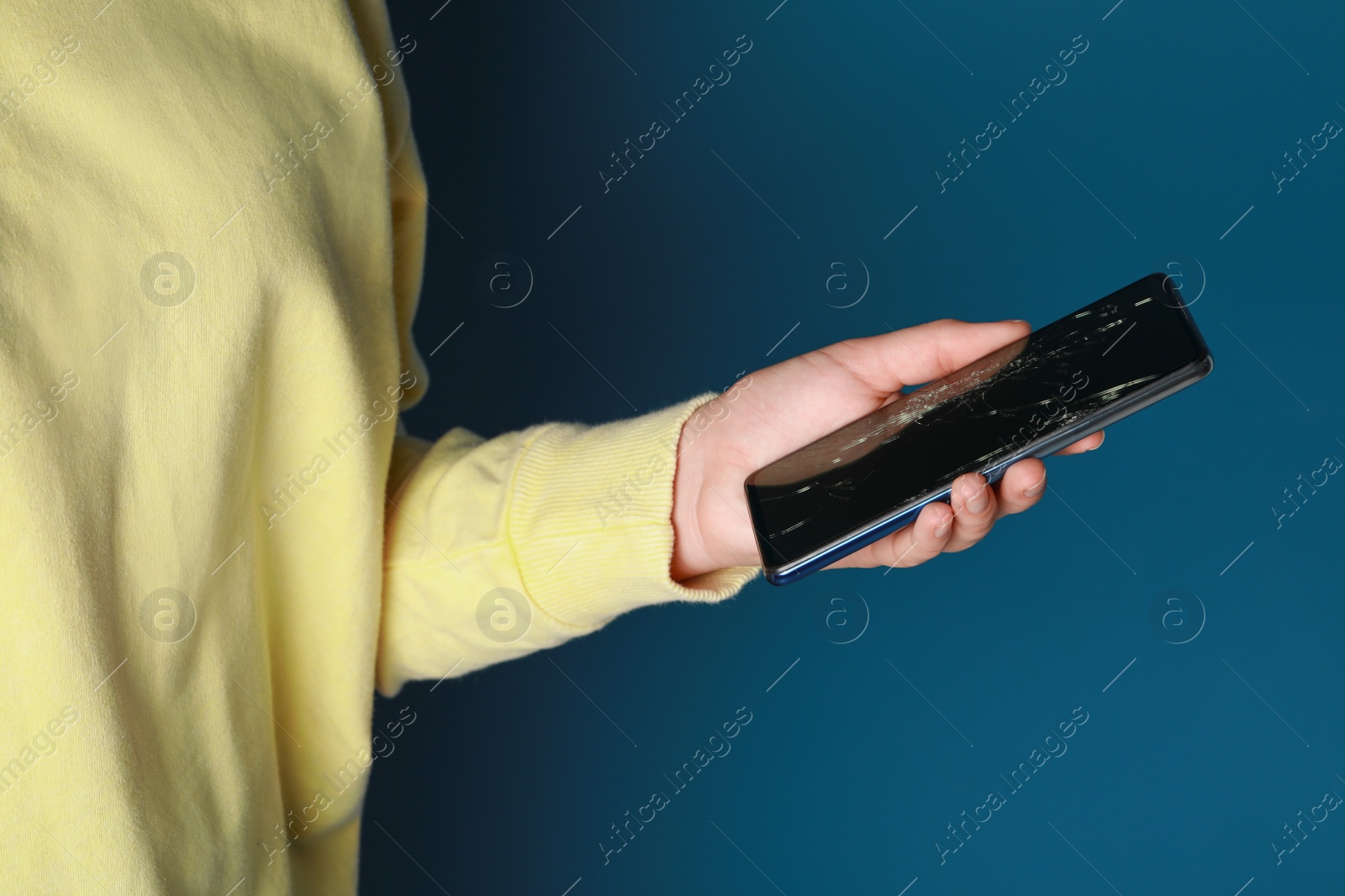 Photo of Woman holding damaged smartphone on light blue background, closeup. Device repairing