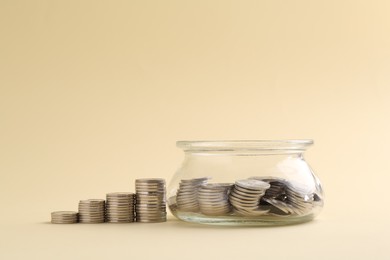 Photo of Financial savings. Coins and glass jar on beige background