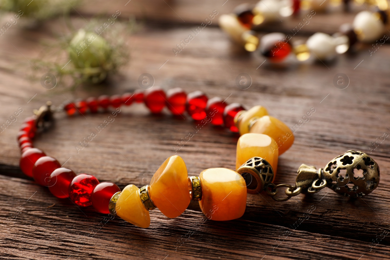 Photo of Beautiful bracelet with gemstones on wooden table, closeup