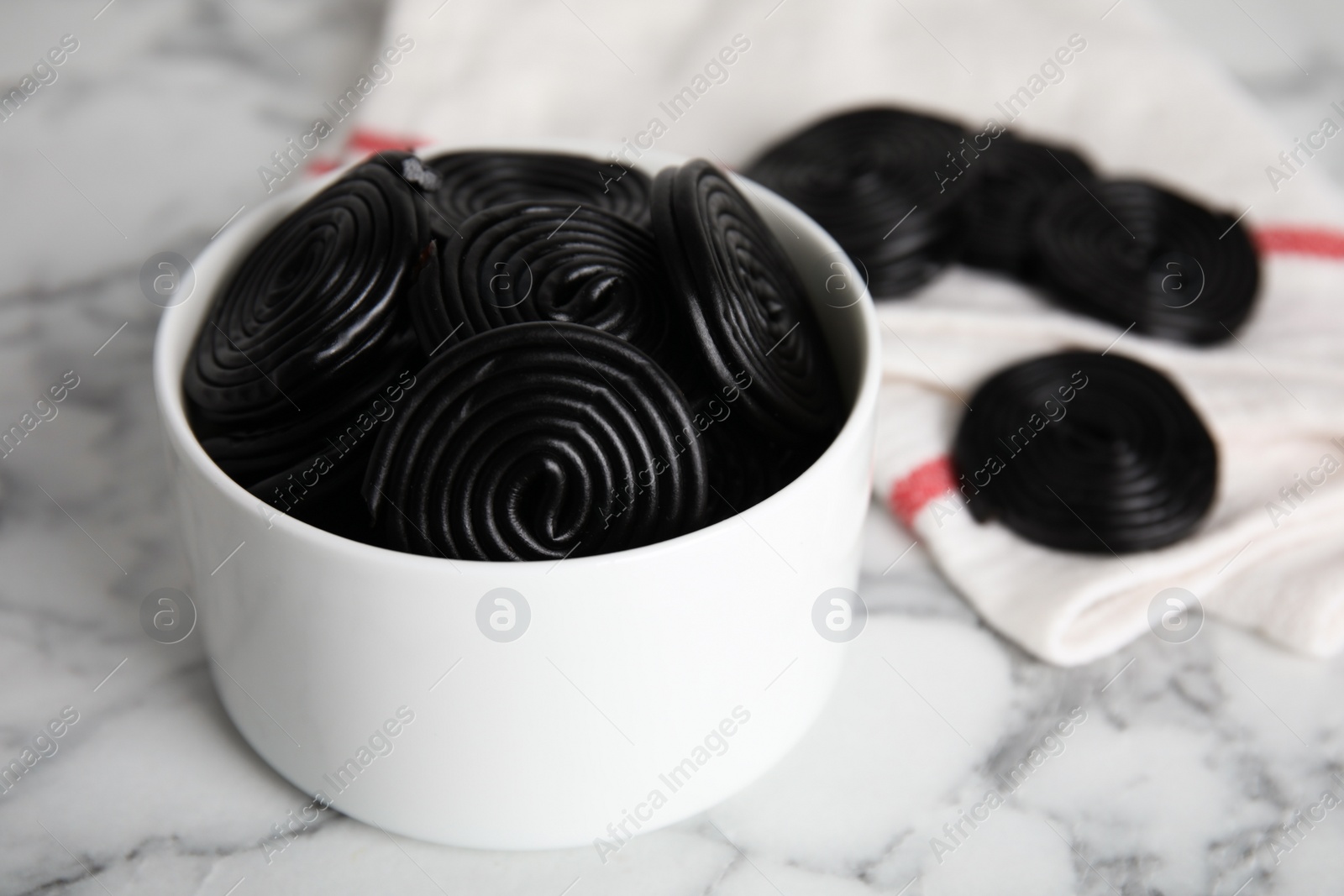 Photo of Tasty black liquorice candies on white marble table, closeup