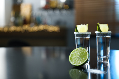 Mexican Tequila with salt and lime slices on black table at bar. Space for text