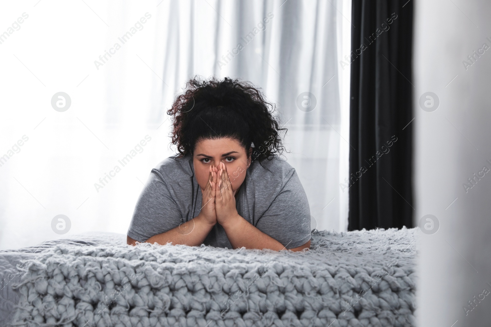 Photo of Depressed overweight woman on bed at home