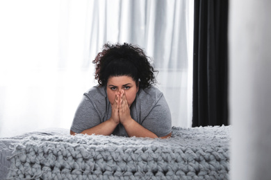 Photo of Depressed overweight woman on bed at home