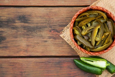 Photo of Fresh and pickled green jalapeno peppers on wooden table, flat lay