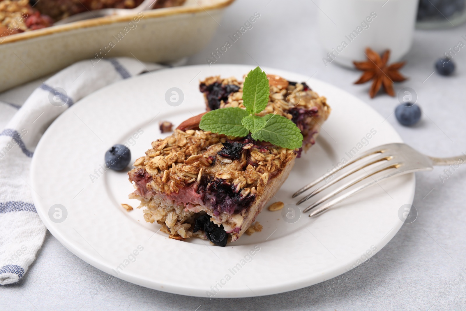 Photo of Tasty baked oatmeal with berries on light table, closeup