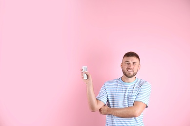 Photo of Young man with air conditioner remote on color background, copy space text