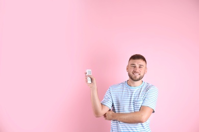 Young man with air conditioner remote on color background, copy space text