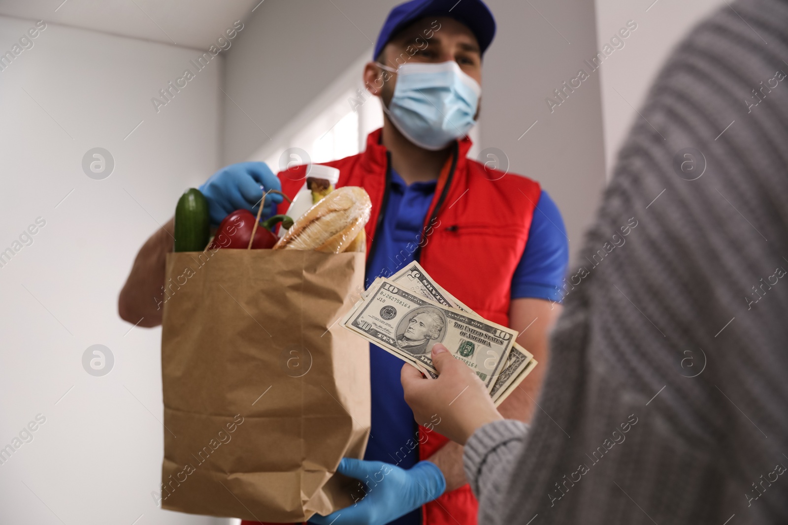 Photo of Young woman giving tips to courier indoors, closeup