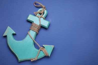 Photo of Wooden anchor figure on blue background, above view. Space for text