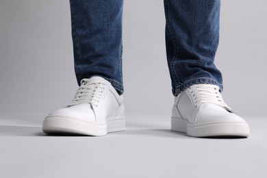 Photo of Man wearing stylish white sneakers on grey background, closeup