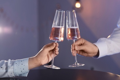 Photo of Man and woman with glasses of champagne on color background, closeup