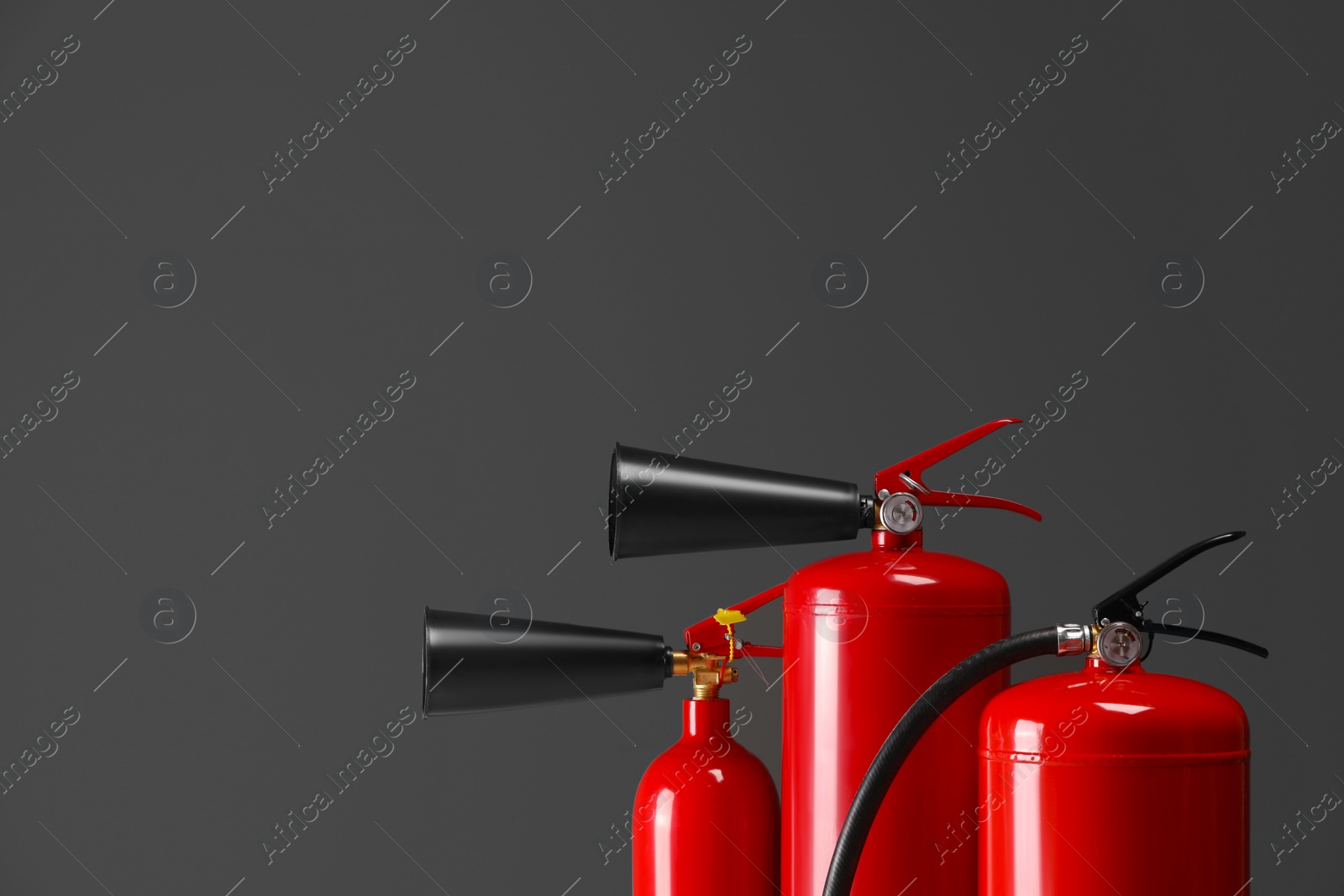 Photo of Fire extinguishers on grey background, closeup with space for text