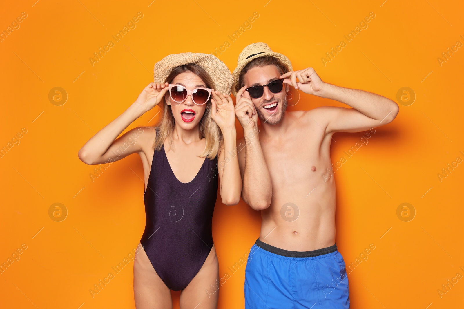 Photo of Happy young couple in beachwear and sunglasses on color background