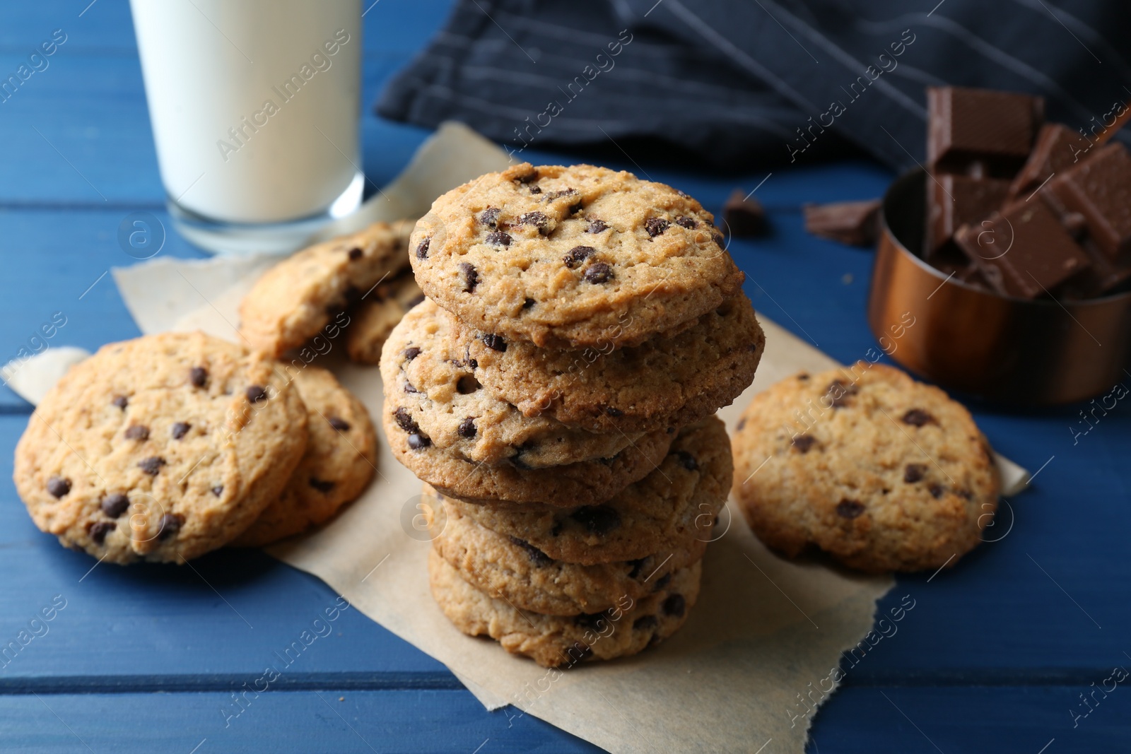 Photo of Tasty chocolate chip cookies and glass of milk on blue wooden table, closeup