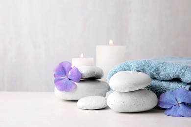 Photo of Composition with zen stones, towel and candles on table against light background. Space for text