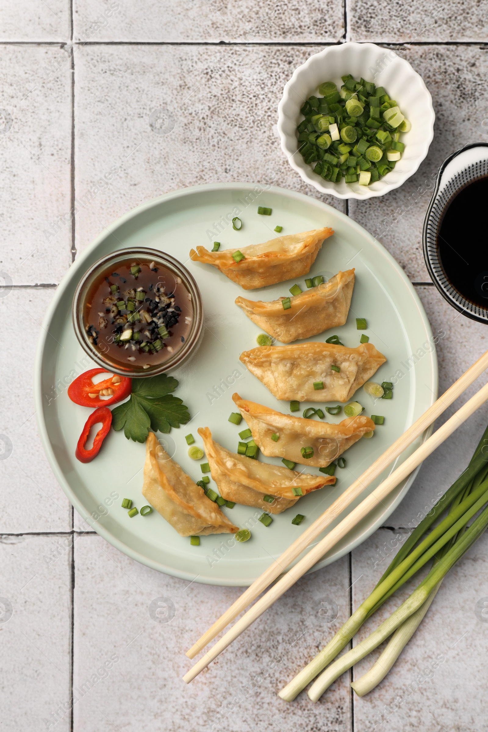 Photo of Delicious gyoza (asian dumplings) served on light tiled table, flat lay