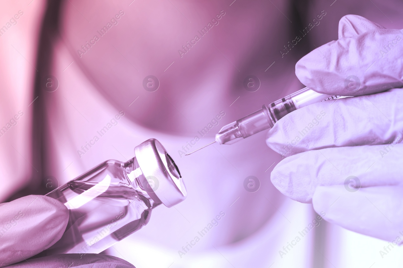Image of Doctor filling syringe with medication from vial, toned in pink
