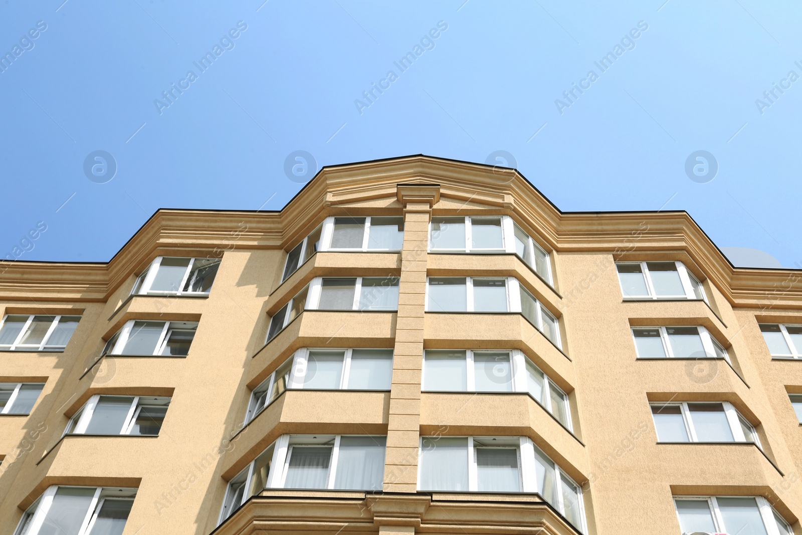 Photo of Exterior of multi storey apartment building against blue sky, low angle view