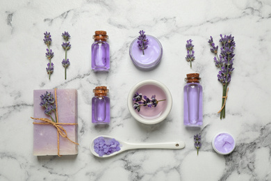 Cosmetic products and lavender flowers on white marble table, flat lay