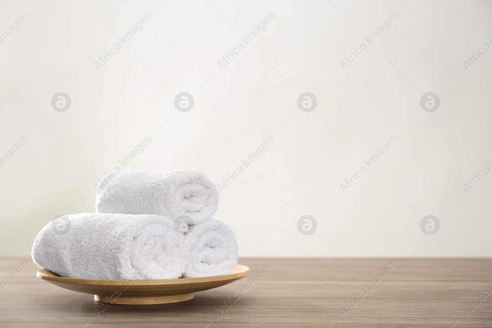 Photo of Fresh rolled towels on wooden table. Space for text