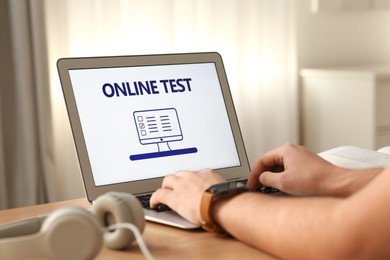 Man taking online test on laptop at desk indoors, closeup