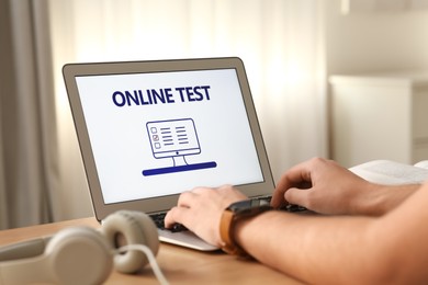 Photo of Man taking online test on laptop at desk indoors, closeup