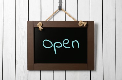 Image of Small chalk board with word Open on white wooden wall