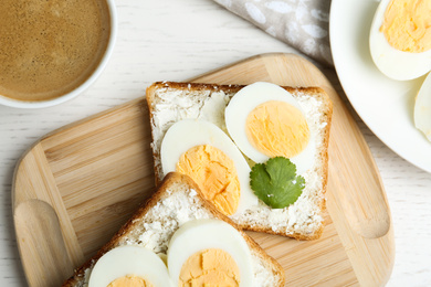 Photo of Tasty egg sandwiches served with coffee on white wooden table, flat lay