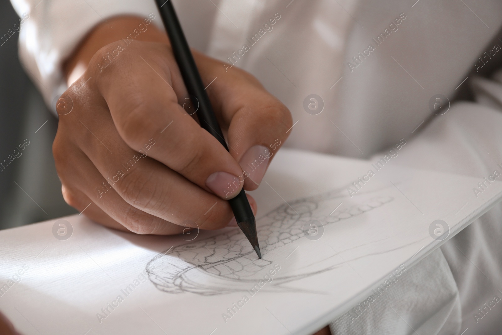 Photo of Man drawing snake with pencil in notepad, closeup