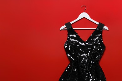 Photo of Beautiful dress and hangers on red background, flat lay. Rental clothing service