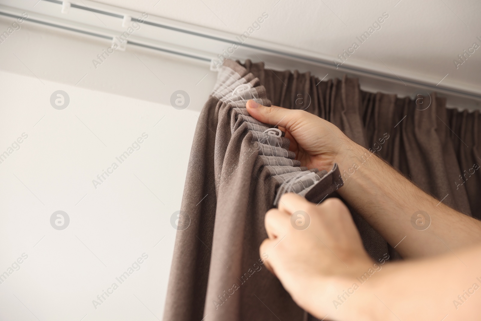 Photo of Worker hanging window curtain, low angle view