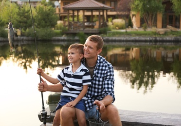 Photo of Dad and son fishing together on sunny day