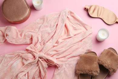 Flat lay composition with fluffy slippers and robe on pink background. Comfortable home outfit