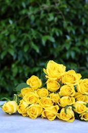 Beautiful bouquet of yellow roses on light table outdoors, space for text