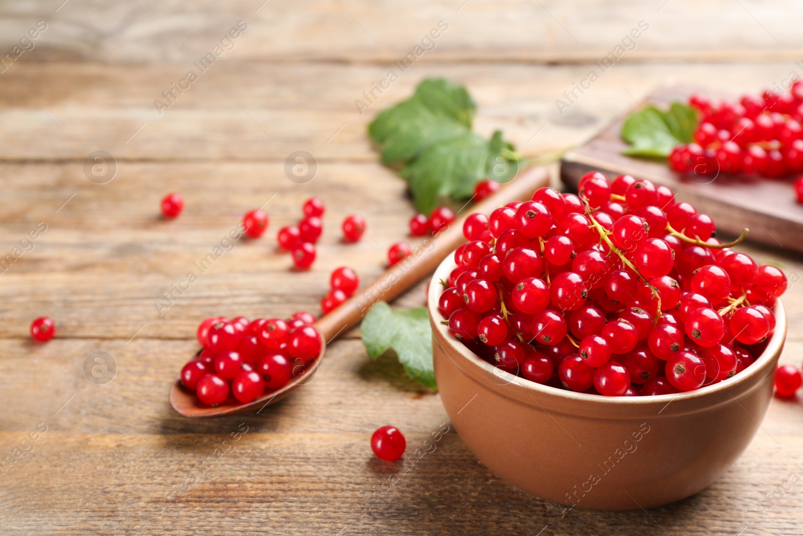 Photo of Delicious red currants on wooden table. Space for text