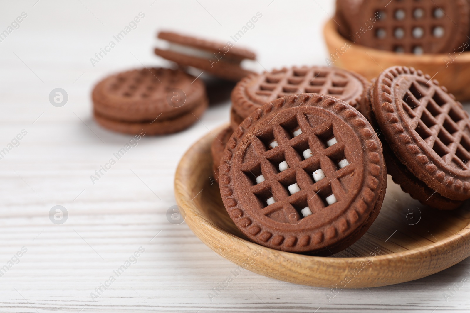 Photo of Tasty chocolate sandwich cookies with cream on white wooden table, closeup. Space for text