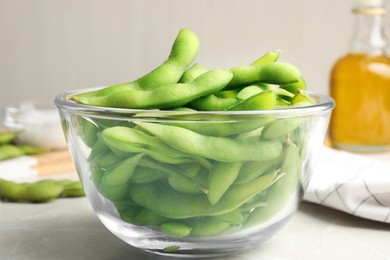 Photo of Bowl with green edamame beans in pods on light grey table