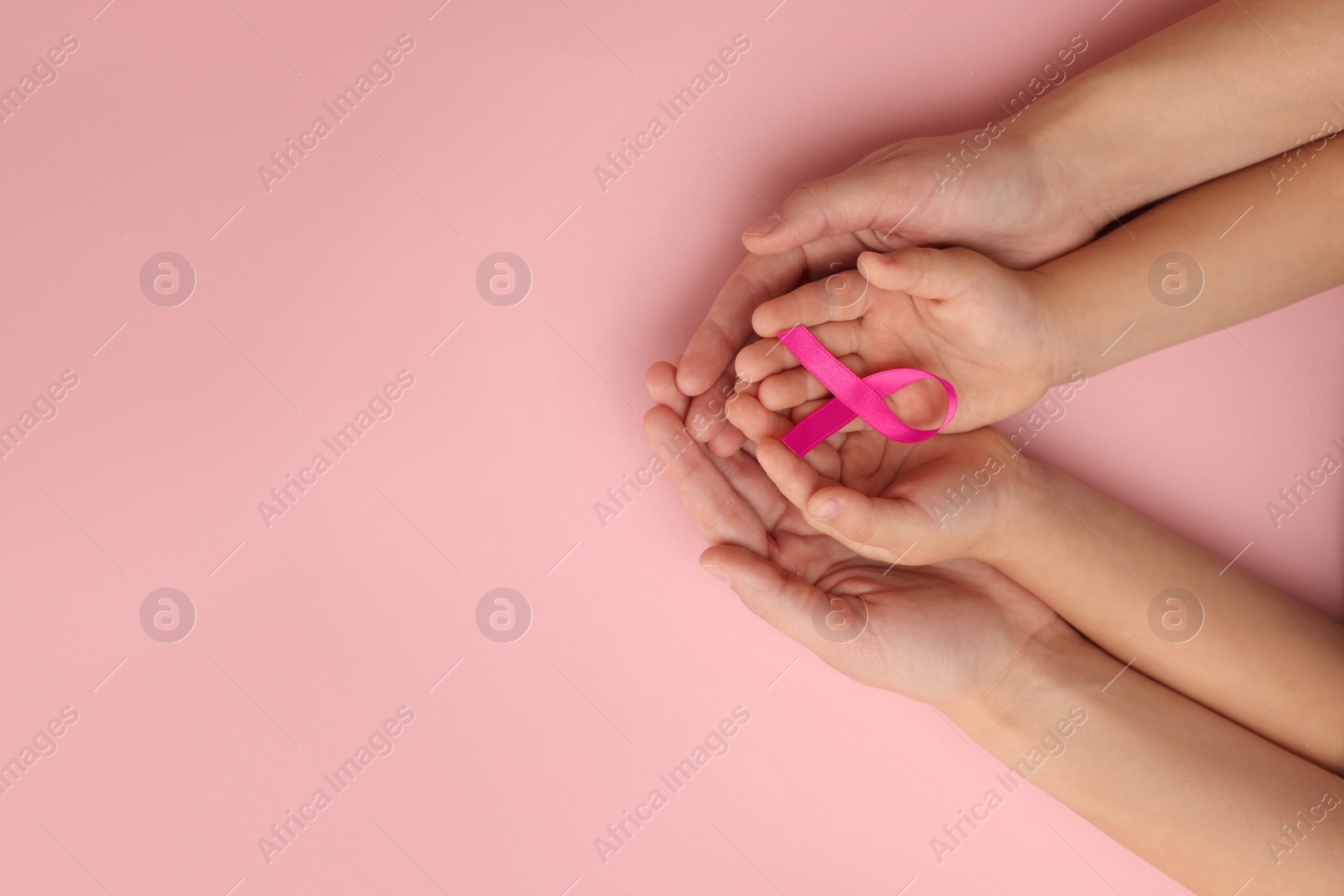 Photo of Woman and child holding pink ribbon on color background, top view with space for text. Breast cancer awareness