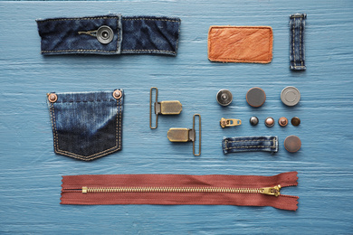 Photo of Flat lay composition with garment accessories and cutting details for jeans on light blue wooden background